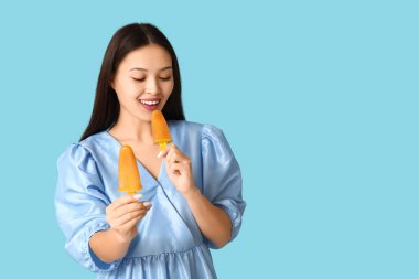 Mavi arka planda mango dondurmalı güzel bir Asyalı kadın.