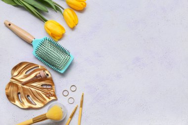 Makyaj ürünleriyle saç fırçası ve beyaz arka planda lale çiçekleri