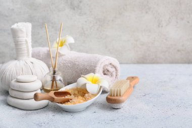 Bitkisel çanta, havlu, bir kase deniz tuzu, spa taşları, tesisat çiçekleri ve grunge arkaplanda sazlık yayıcı ile güzel bir kompozisyon.