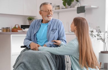 Bakıcı, huzurevinde tekerlekli sandalyedeki yaşlı adamla birlikte.