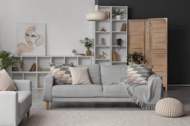 Oturma odasında rahat koltuklar ve raf ünitesi var.