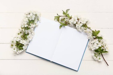 Çiçek açan güzel dallar ve beyaz ahşap arka planda bir defter.