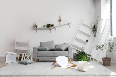 Kanepesi, rafları ve bitkileri olan dağınık bir oturma odası.