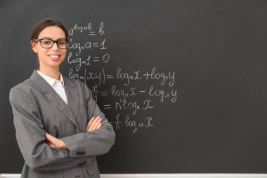 Sınıfta yazı tahtasının yanında genç bayan matematik öğretmeni.