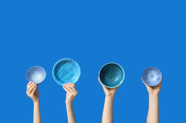 Mavi arkaplanda boş tabakları tutan eller