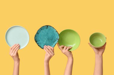 Sarı arkaplanda boş tabakları tutan eller