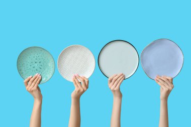 Mavi arkaplanda boş tabakları tutan eller