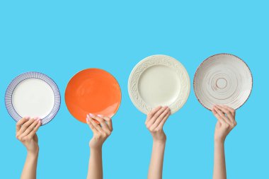 Mavi arkaplanda boş tabakları tutan eller