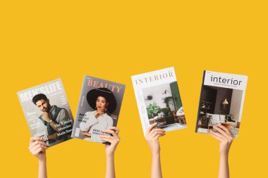 Sarı arka planda farklı dergileri olan kadın elleri