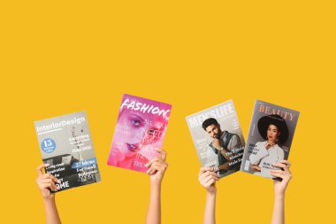 Sarı arka planda farklı dergileri olan kadın elleri