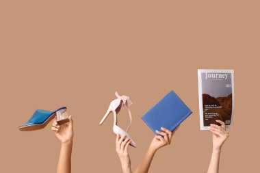 Dergi, kitap ve yüksek topuklu kadın eli kahverengi arka planda.