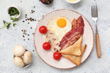 Kızarmış yumurta, pastırma, tost, domates, mantar ve biberli tabak beyaz grunge arka planda. Yakın çekim.
