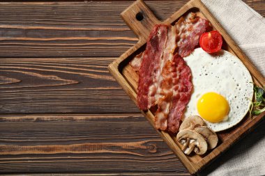 Tahta arka planda sahanda yumurta, pastırma ve mantar var. Üst görünüm