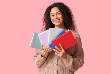 Pembe arka plan kitapları olan genç bir Afro-Amerikalı kadın.