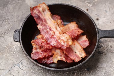 Gri arka planda kızarmış pastırma dilimleri.