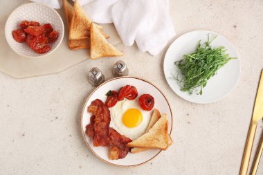 Beyaz arka planda kızarmış yumurta, pastırma, tost ve kurutulmuş domates tabağı. Üst görünüm