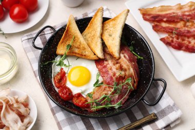 Tavada yumurta, pastırma, tost ve beyaz arka planda kurutulmuş domates. Üst görünüm