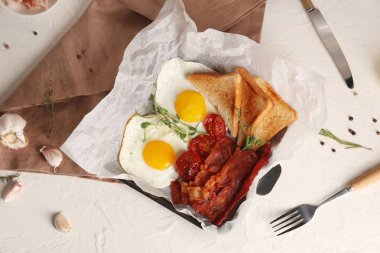 Beyaz masadaki parşömen kağıdında kızarmış pastırma ve yumurta. Üst görünüm