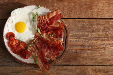 Yağda yumurta, pastırma ve ahşap arka planda kurutulmuş domates tabağı. Üst görünüm