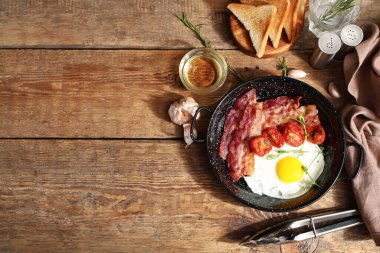 Kızarmış yumurta, pastırma ve ahşap arka planda kurutulmuş domates. Üst görünüm