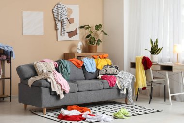 Gri kanepesi ve dağınık kıyafetleri olan dağınık bir oturma odası.