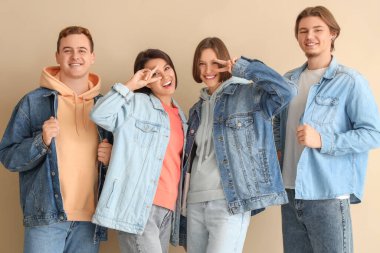 Bej arka planda kot giymiş bir grup genç.