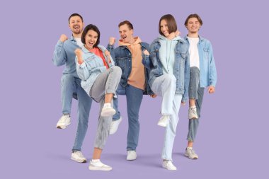 Eflatun arka planda kot giymiş bir grup mutlu genç.