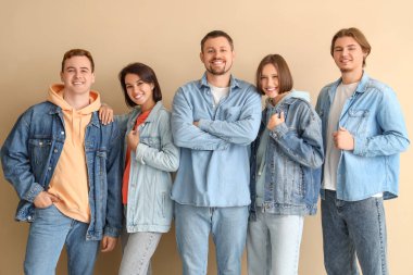 Bej arka planda kot giymiş bir grup genç.