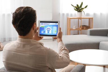 Akıllı ev güvenlik sistemi kontrol paneli olan genç bir adam.