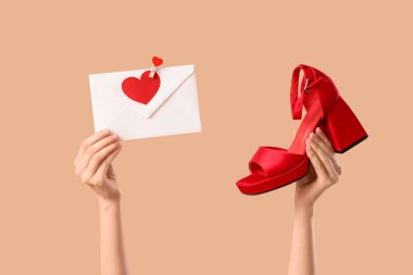 Zarflı kadın eller ve bej arka planda yüksek topuklu ayakkabılar. Sevgililer Günü kutlaması