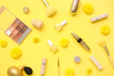 Makyaj ürünleri, tırnak cilası ve sarı arka planda çiçekler.