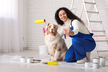 Üniformalı mutlu Afro-Amerikan ressam ve sevimli Avustralyalı çoban köpeği evde tamir sırasında selfie çekiyor.