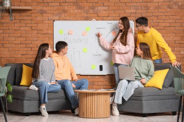 Gençler ofiste beyaz tahtanın yanında müzakere ediyorlar