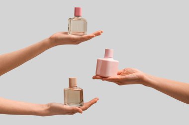 Gri arka planda parfüm şişeleri olan kadın elleri.