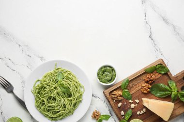 Lezzetli soslu makarna tabağı, bir kase sos ve mermer zemin üzerine malzemeler.