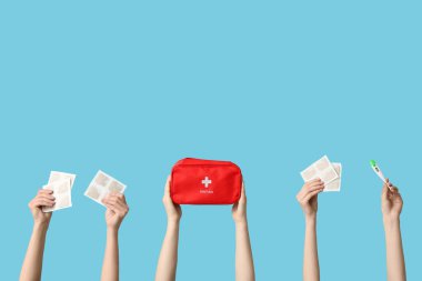 Hardal sıva, termometre ve mavi arka planda ilk yardım çantası olan kadın elleri.