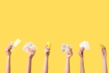 Hardal alçılı, haplı, ilaç kutulu ve sarı arka planda tıbbi maskeli kadınlar.