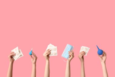 Hardal alçılı kadın elleri, tıbbi maske ve pembe arka planda lavman.