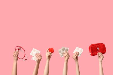 Hardal sıva, ilaç kutusu, steteskop ve pembe arka planda ilk yardım çantası olan kadın elleri.