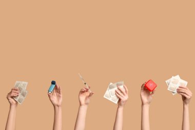 Hardal alçılı kadın elleri, ilaç kutusu, astım spreyi ve bej arka planda şırınga.