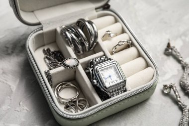 Gri arka planda güzel gümüş mücevherleri ve kol saati olan bir organizatör.