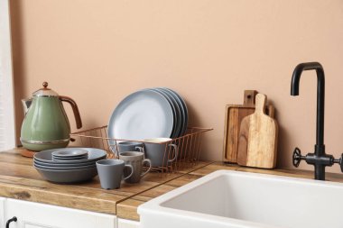 Mutfakta lavabonun yanında temiz gri tabakları ve bardakları olan tutucu.