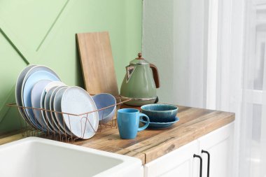 Mutfak tezgahında temiz tabaklar ve elektrikli su ısıtıcısı olan tutucu.