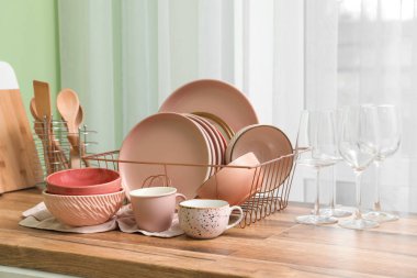 Mutfak penceresinin yanındaki tezgahta temiz pembe tabakları olan tutucu.