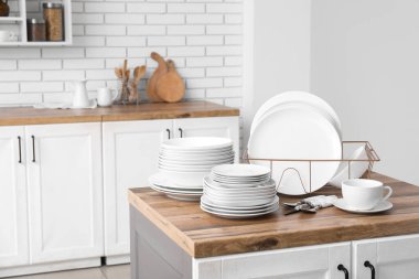 Mutfak tezgahında temiz beyaz tabaklar ve çatal bıçak takımı olan tutucu.