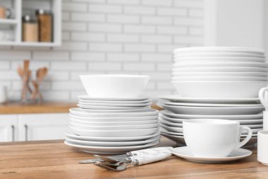 Mutfakta temiz beyaz tabaklar ve çatal bıçak takımı var.