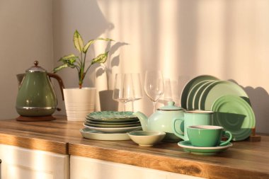 Mutfakta temiz yeşil tabaklar ve elektrikli çaydanlık var.