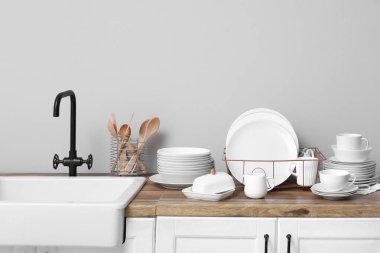 Mutfakta lavabonun yanında temiz beyaz tabakları olan bir tutucu.