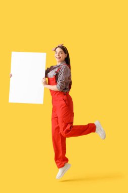 Sarı arka planda boş posteri olan genç bir kadın ressam.