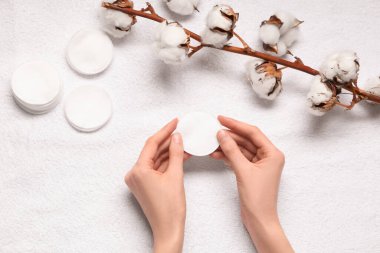 Pamuk yastıklı kadın elleri ve beyaz desenli arka planda pamuk çiçekleri